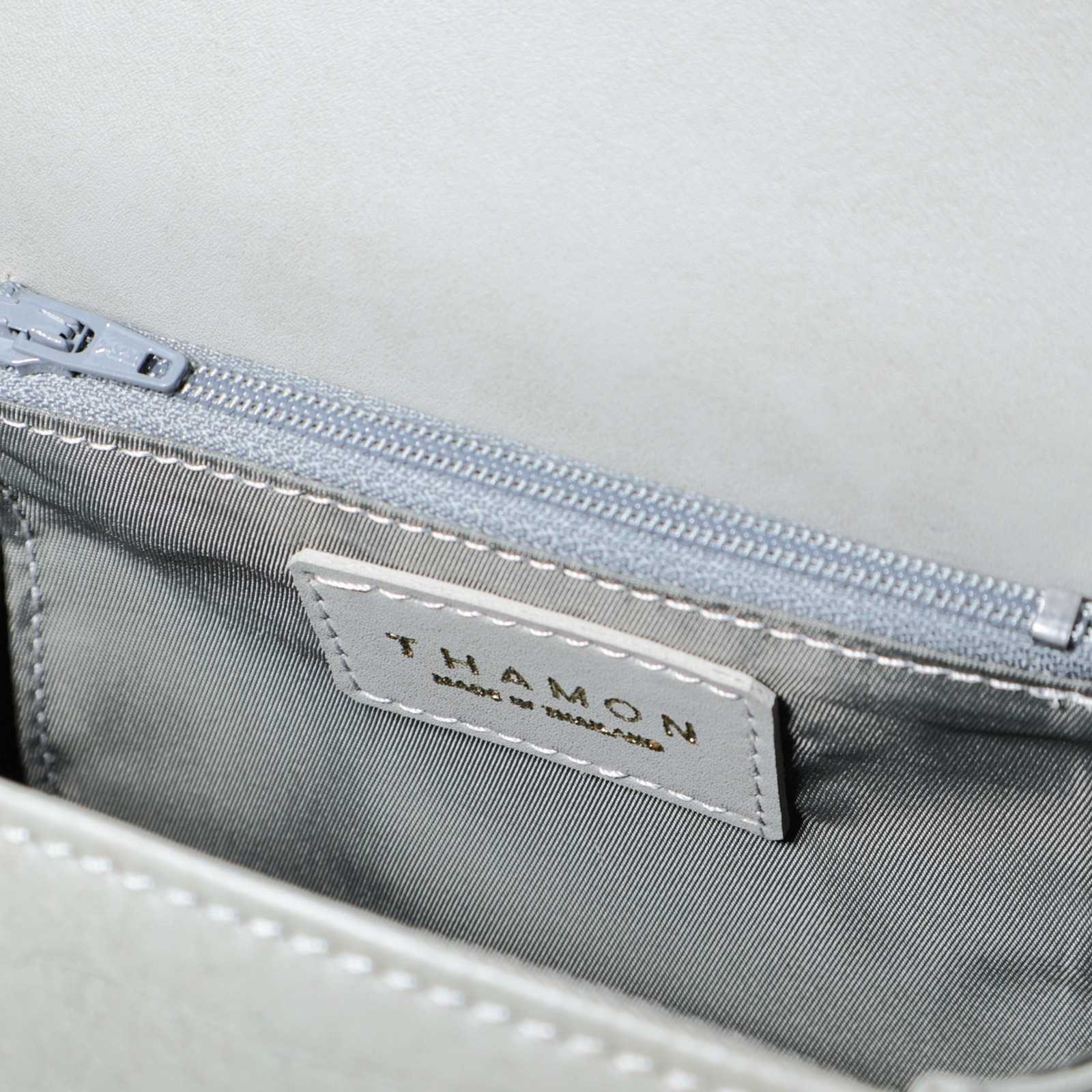 Interior of the Cloud Grey Box Bag in vegan leather, showing grey striped lining, an internal zip pocket, and a THAMON logo label.