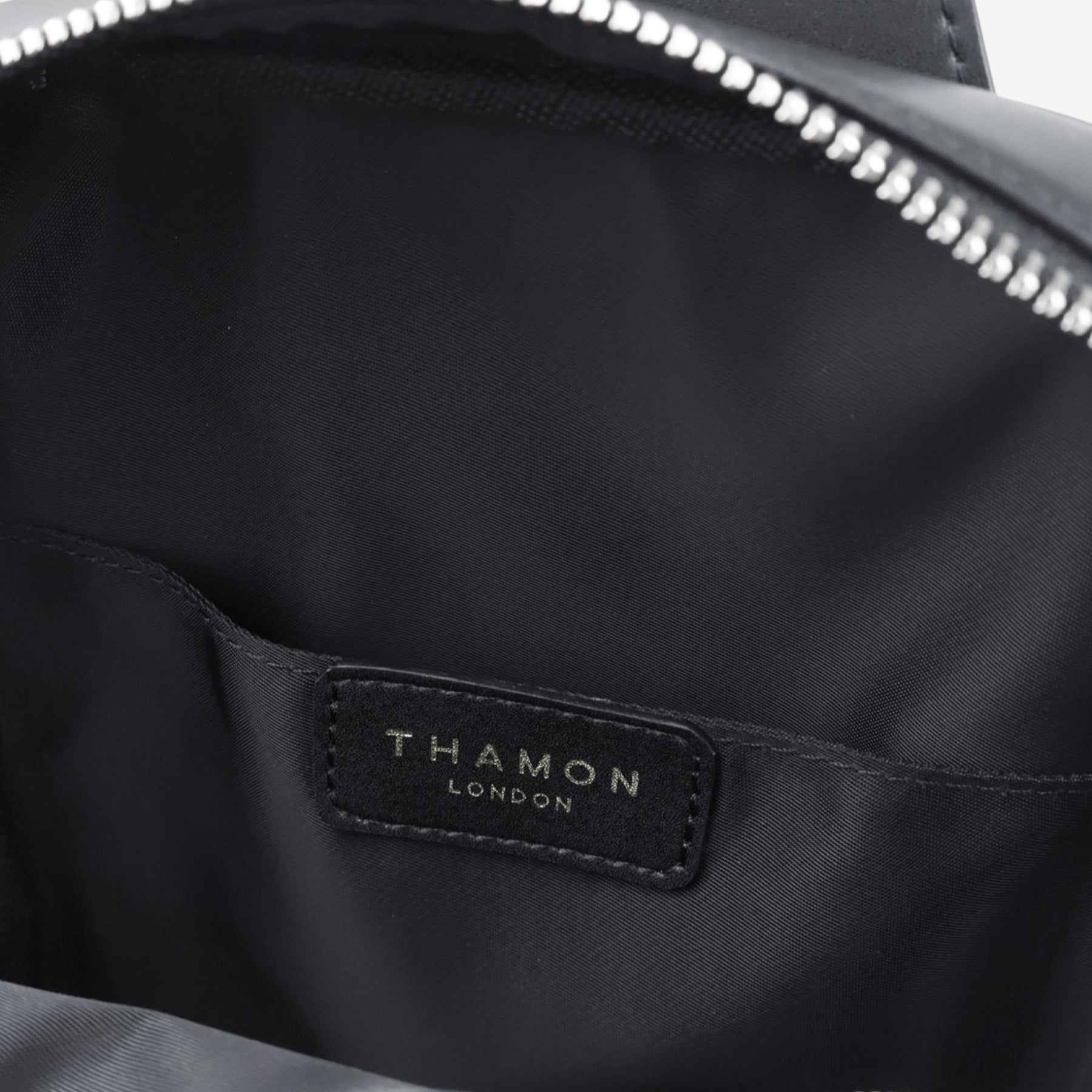Interior view of black Nomad sling bag by Thamon, featuring branded fabric lining and inner pocket