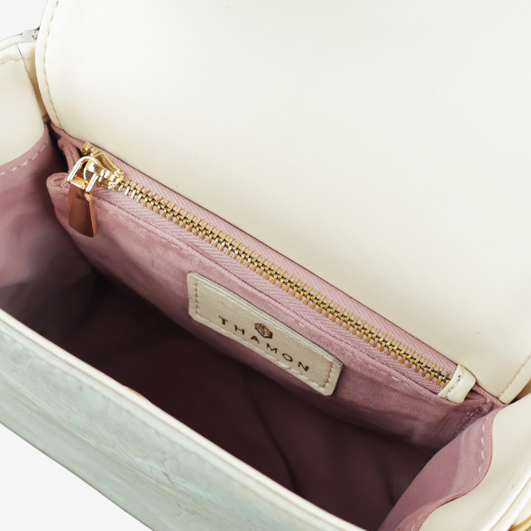 Interior view of the Thamon Pearl Ivory White bag, revealing its vibrant pink lining and interior compartment(s), contrasting with the leaf leather exterior.