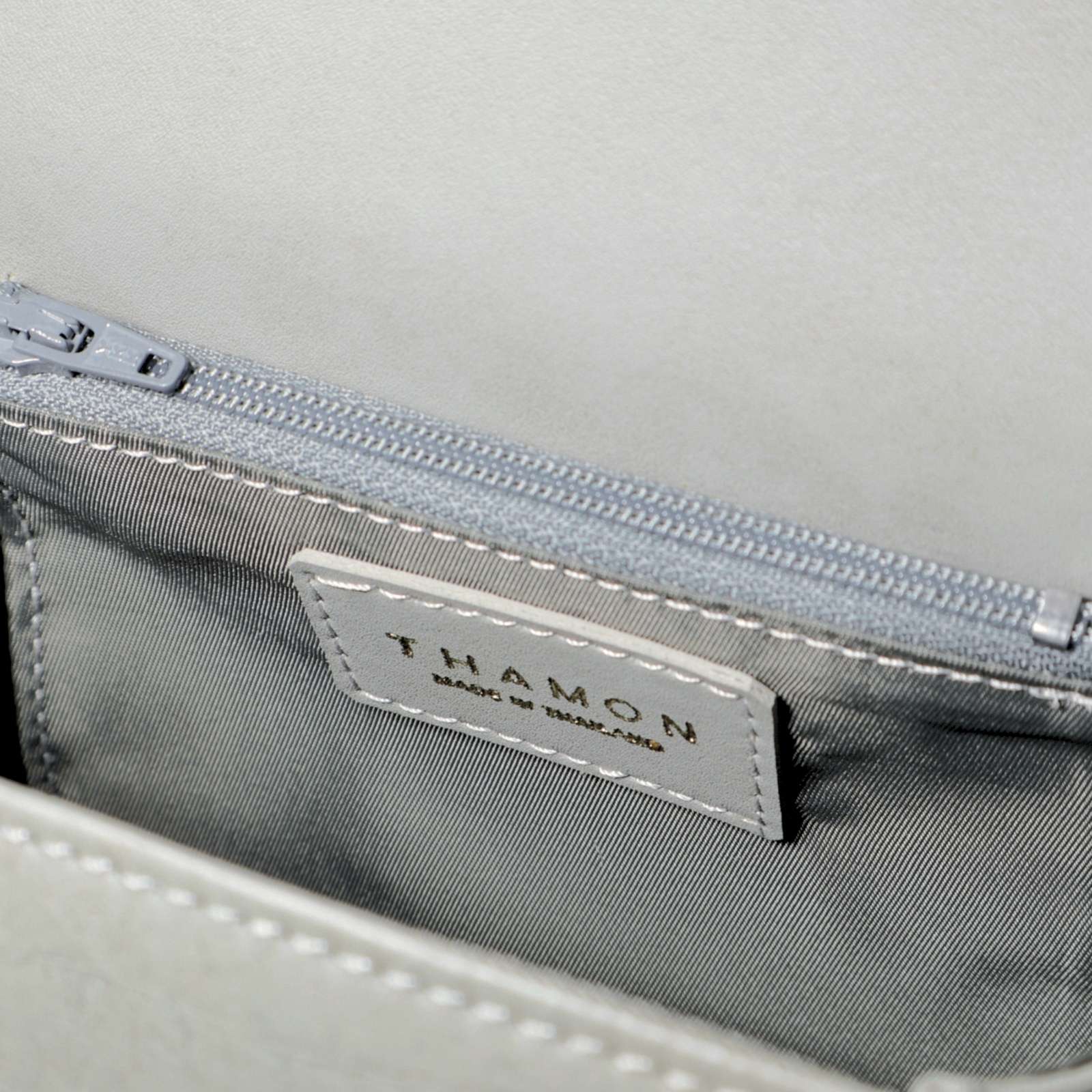 Interior of the Cloud Grey Box Bag in Leaftex, showing the striped lining and internal zip pocket.