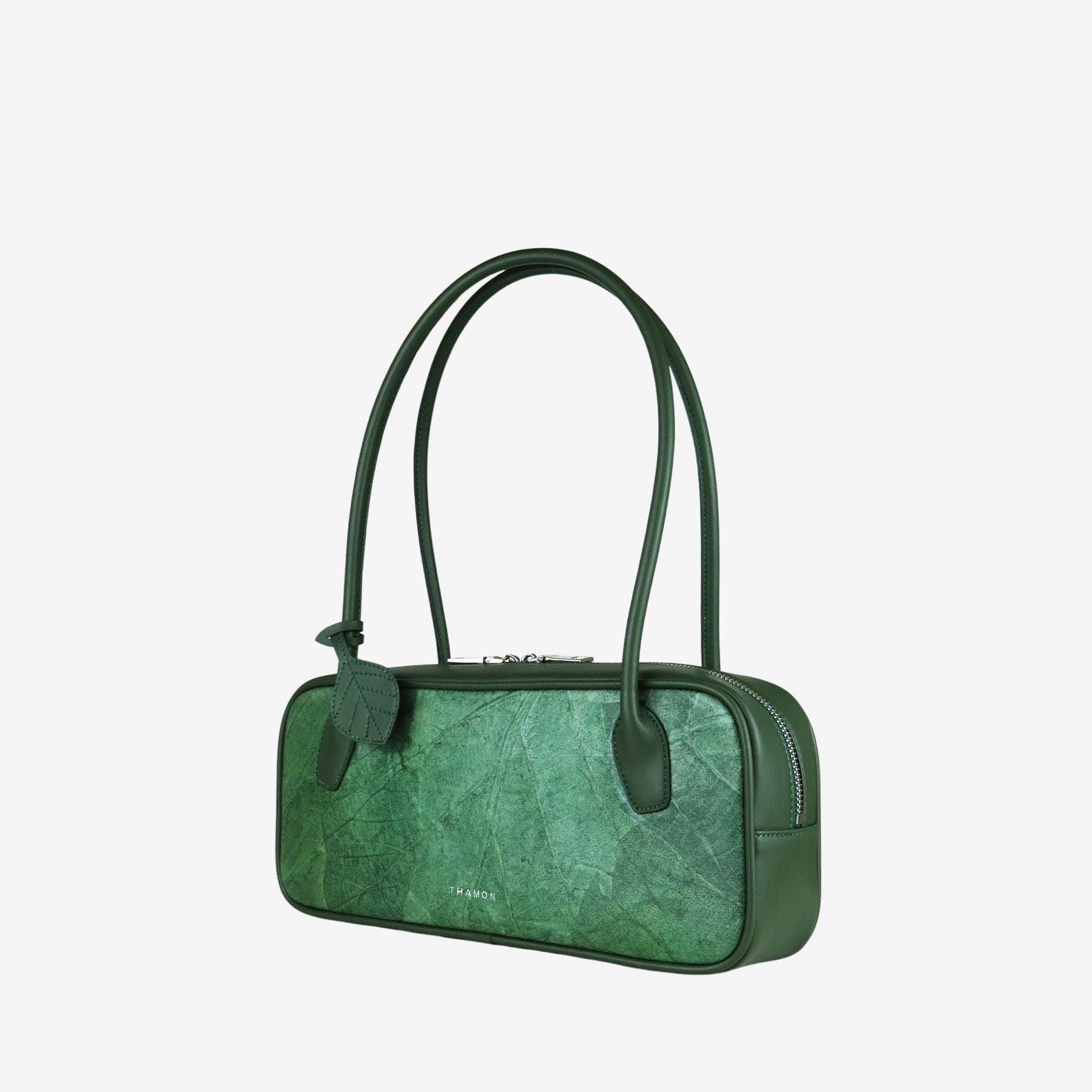 Green leaf-patterned vegan leather shoulder bag with a leaf charm. Sustainable fashion accessory.