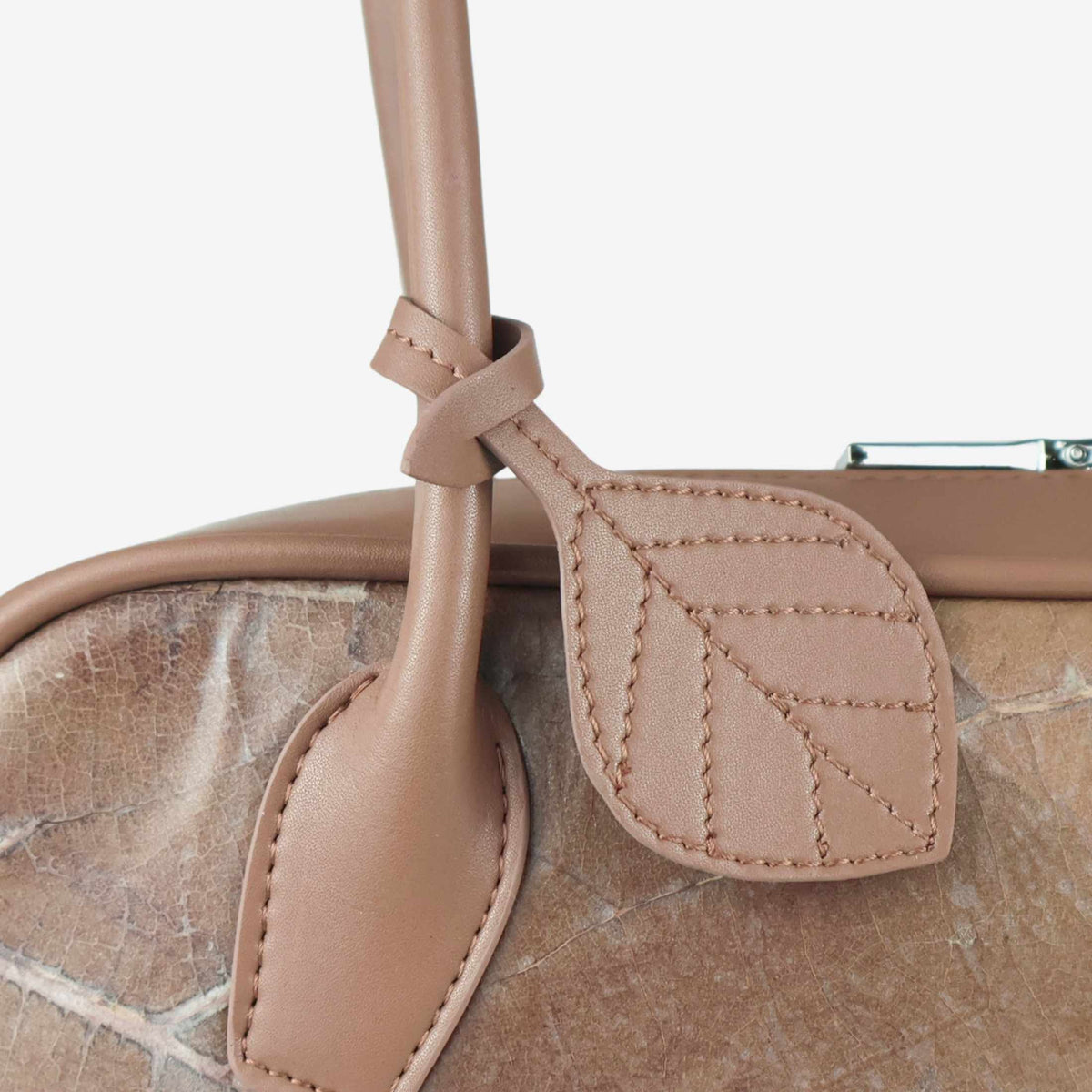 Close-up of the THAMON CRAUGETTE shoulder bag in Taupe, showing the stitched leaf-shaped charm and natural leaf texture.