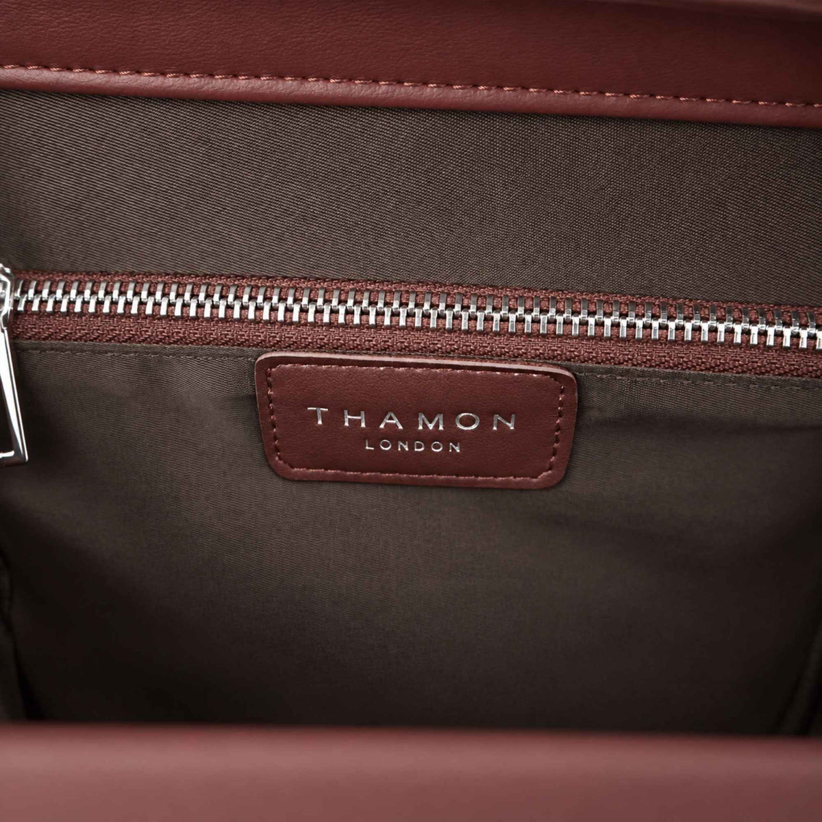 Interior detail of the Ingrid bag in Walnut Brown showing the THAMON London logo, dark taupe lining and silver zip