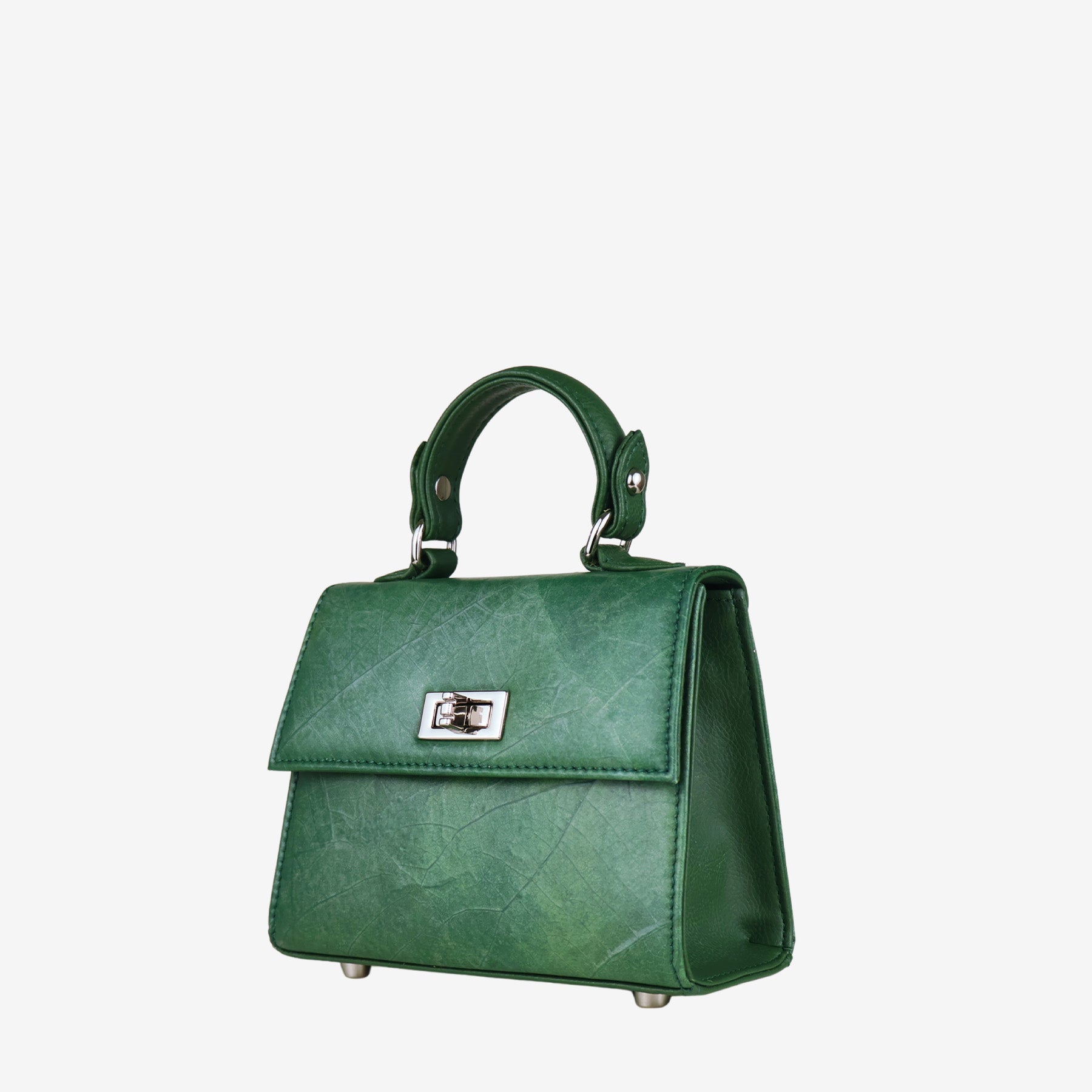 Front view of a structured, deep green women's handbag with a subtle leaf-like texture. The bag features a silver-tone twist-lock closure on the front flap, a single top handle, and four silver-tone metal feet on the bottom. The side panels of the bag are smooth, contrasting with the textured front and back.