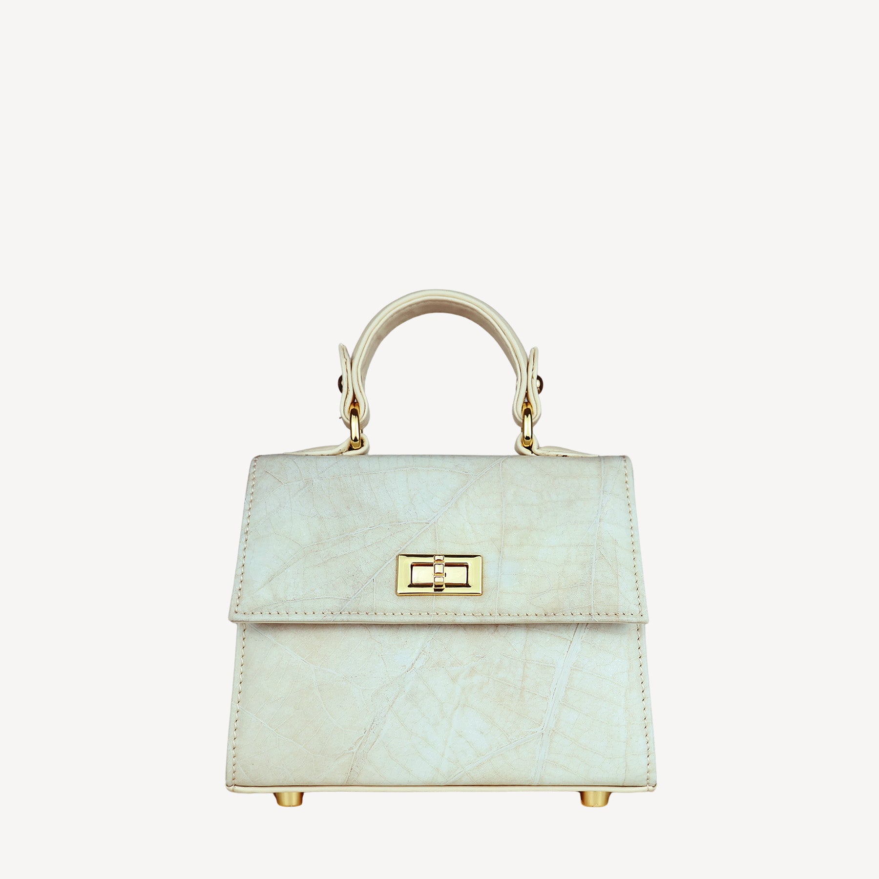 Front view of a structured, cream-colored women's handbag with a subtle leaf-like texture. The bag features a shiny gold-tone twist-lock closure on the front flap and a single top handle connected by matching hardware. The bag's body and flap are made of the textured material, while the sides are smooth. Four gold-tone metal feet are visible on the bottom.