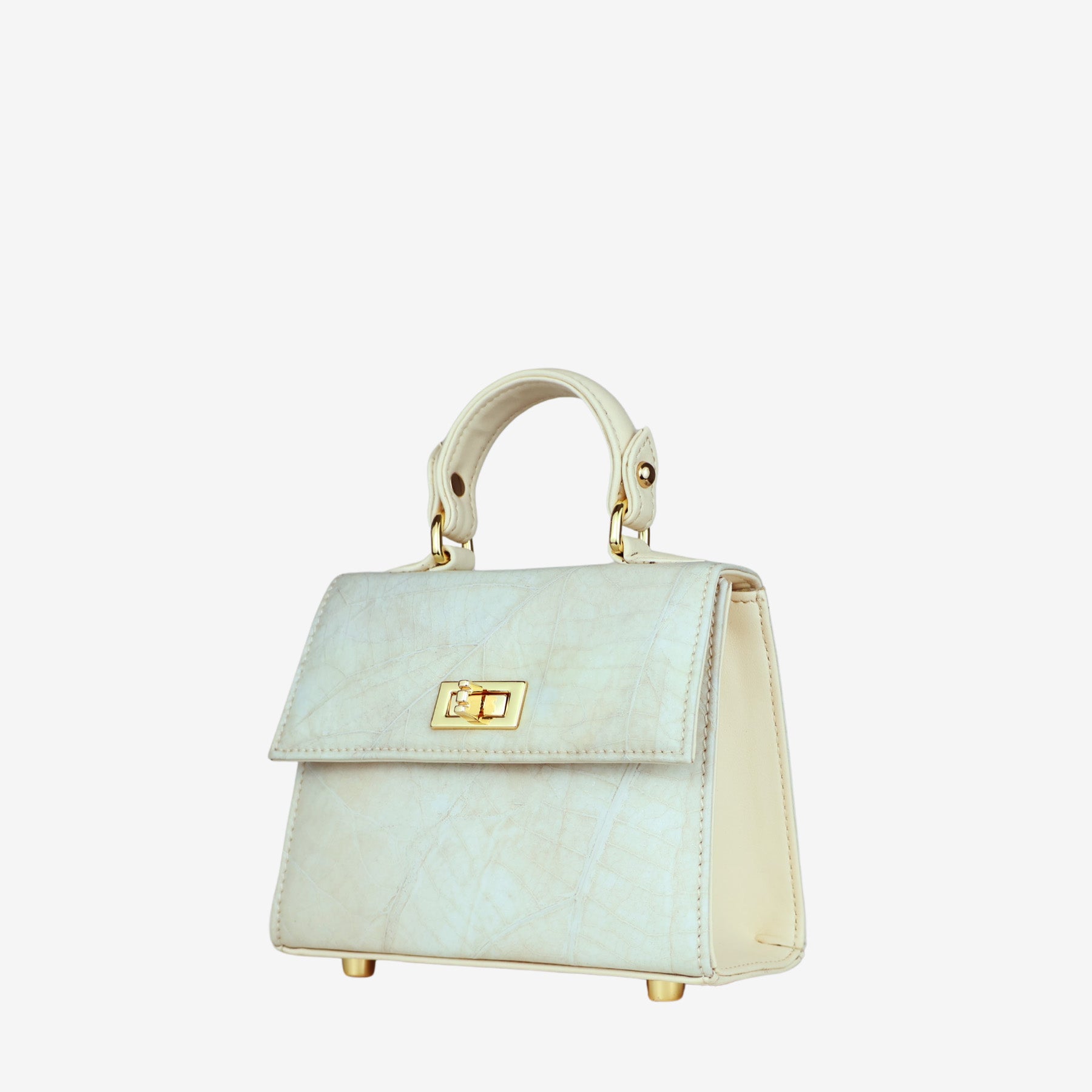 A structured, cream-colored women's handbag is shown in a front view. The bag has a unique, subtle leaf-like texture on the front flap and body, which is complemented by smooth side panels. It features a shiny gold-tone twist-lock closure on the front and a single top handle. Four gold-tone metal feet are visible on the base of the bag, providing protection and stability.