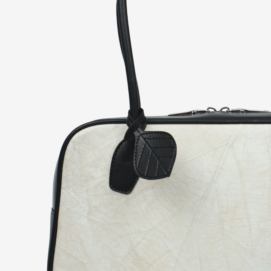Close-up detail of Thamon Boston Shoulder Bag in ivory white Leaftex and black trim.