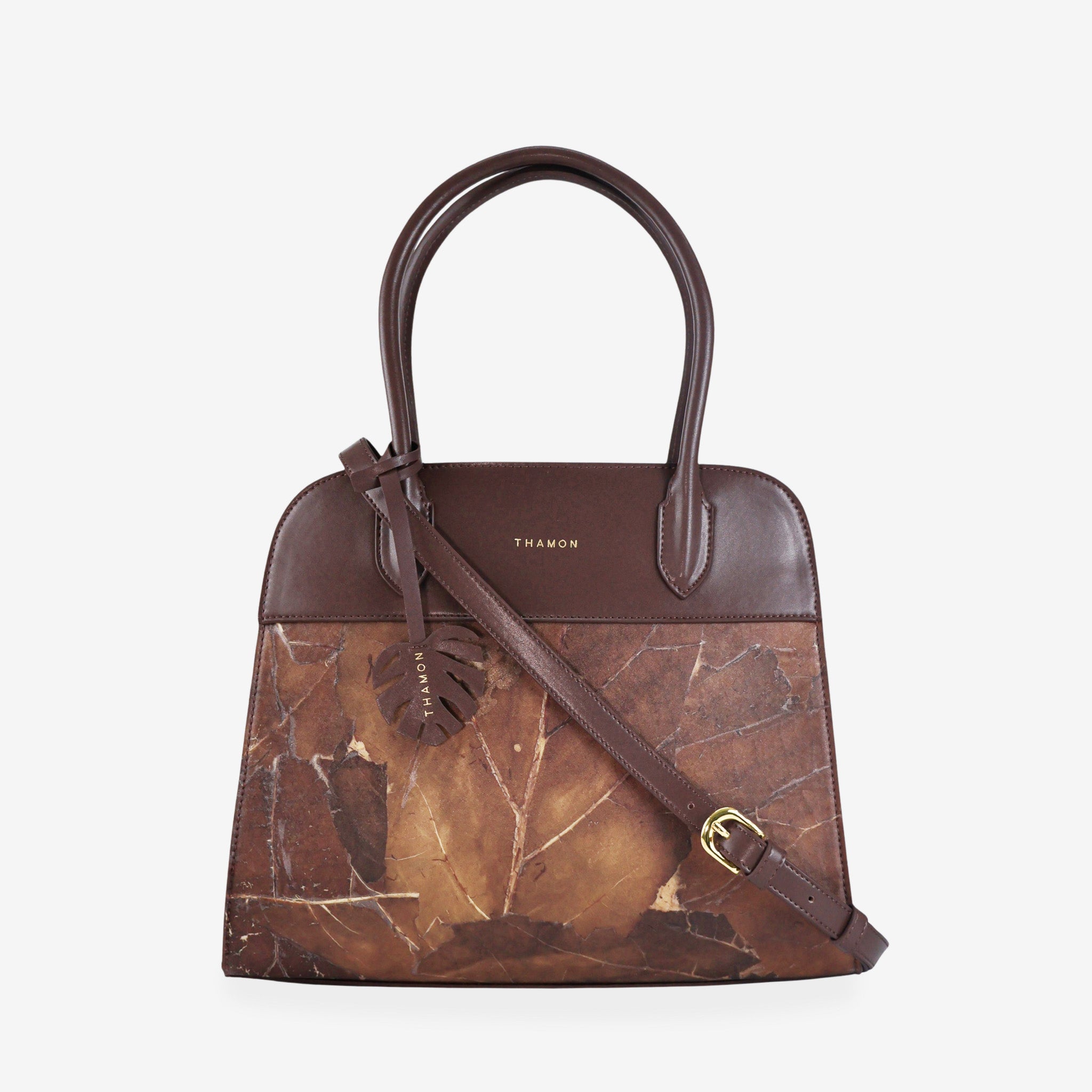Sloane tote bag in spice brown vegan leather with a pressed leaf pattern, featuring an adjustable crossbody strap, sturdy top handles, and a decorative leaf-shaped tag on the front