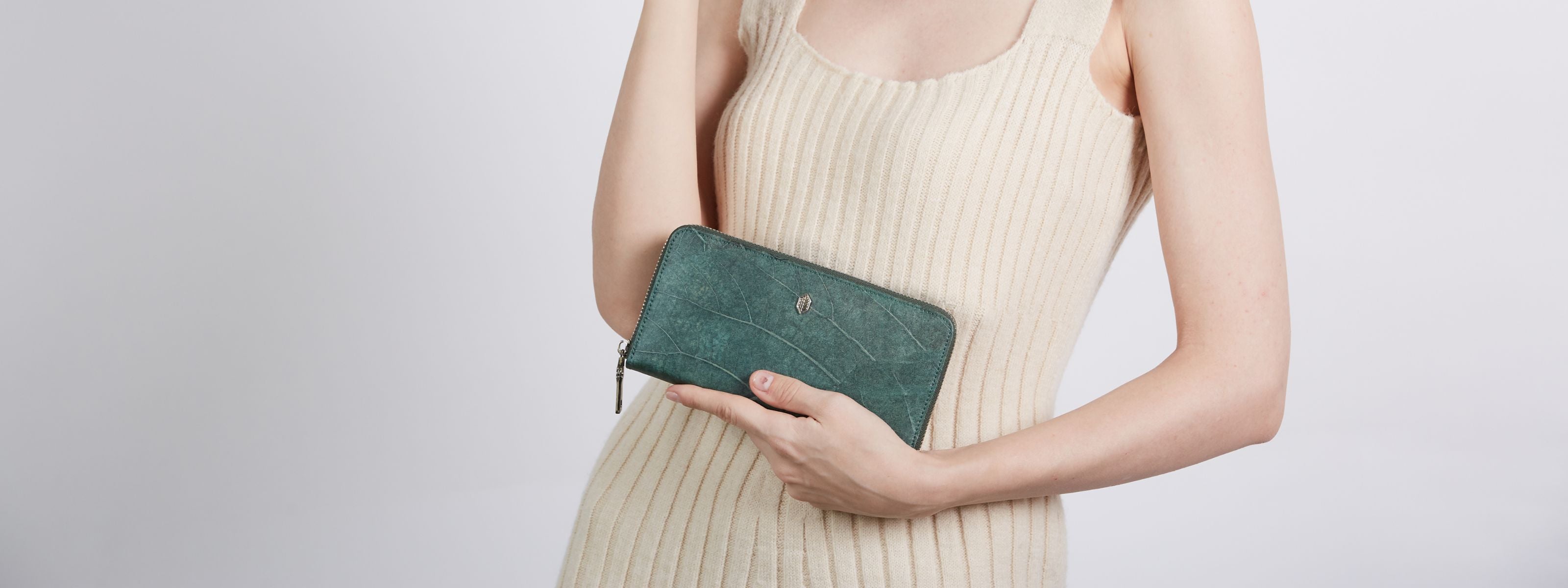 Woman holding forest green zip-around wallet made from Leaftex, featured in Thamon’s vegan wallet collection
