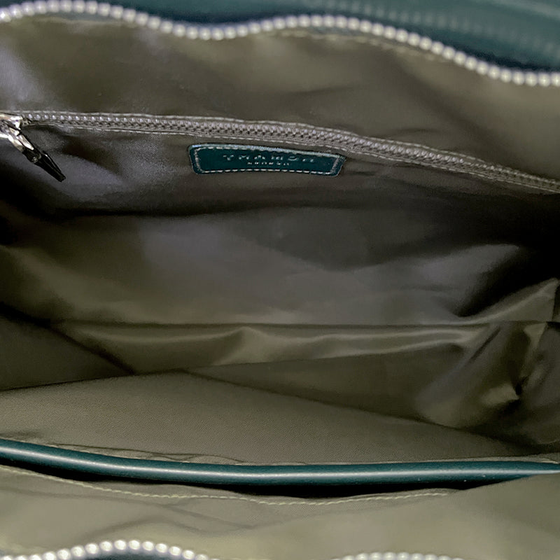 Inside the Thamon forest green Alma tote bag, showcasing a khaki green lining, a vegan leather logo patch, a zip compartment, and a pocket for organized storage.