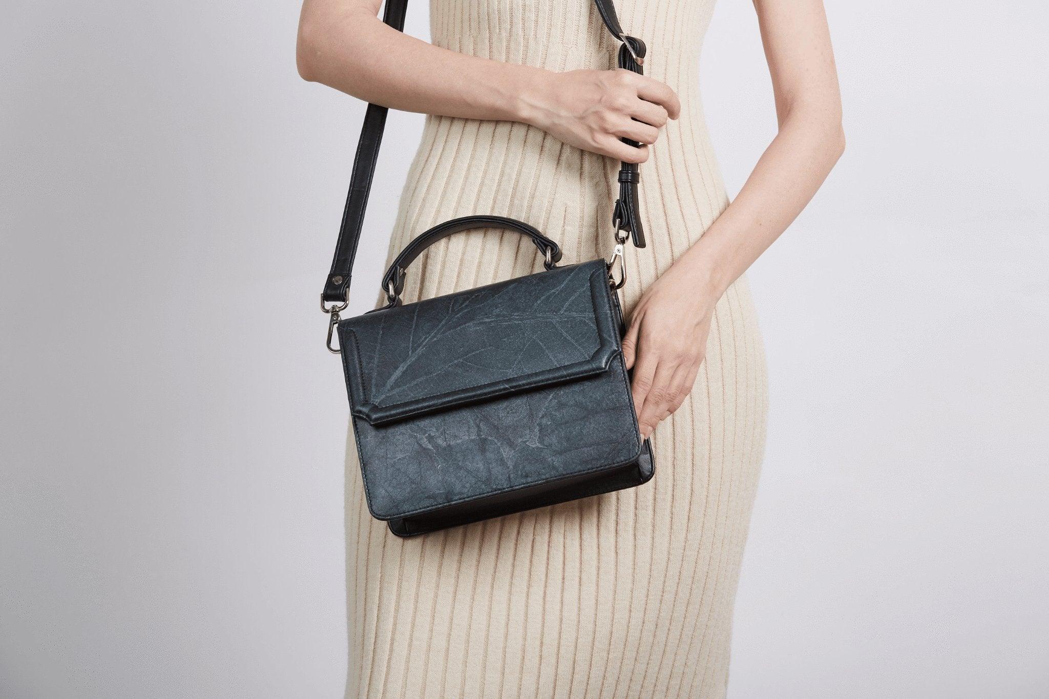 a women in a beige dress is holding black Camden bag.