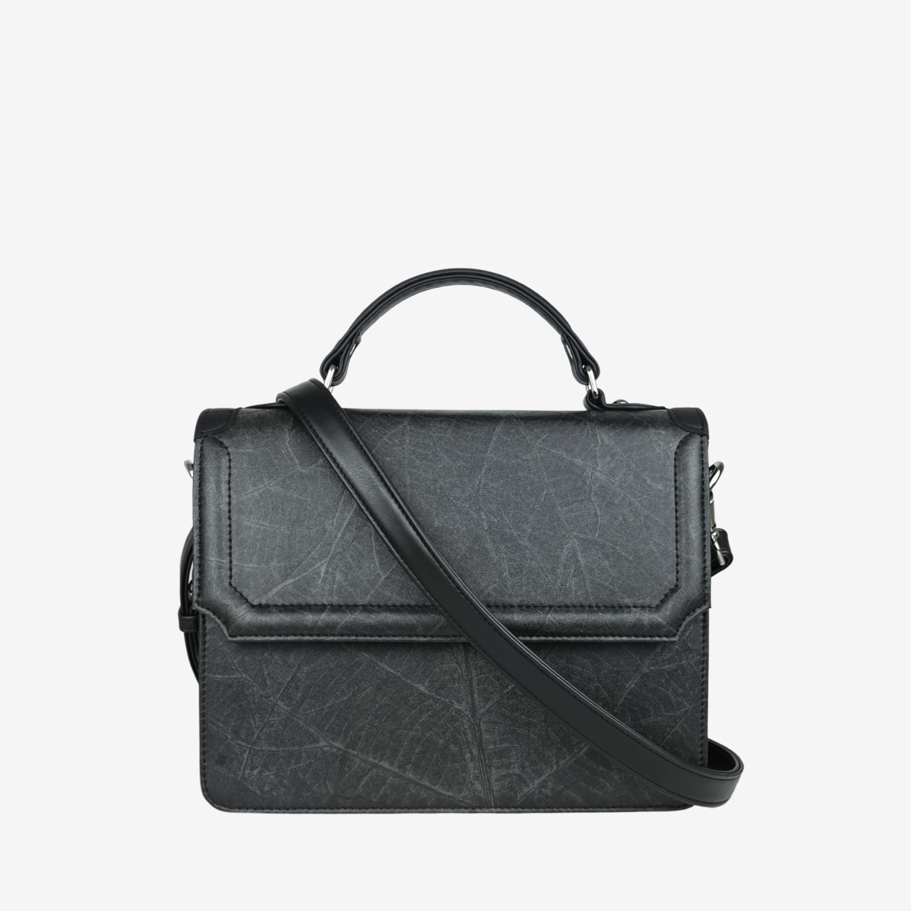 Camden crossbody bag in black Leaftex with adjustable strap draped across front and top handle detail