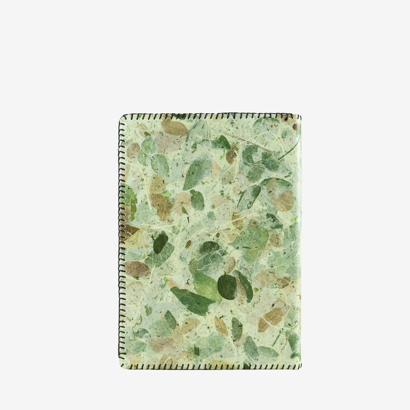 Back view of an A5 refillable notebook cover with a camouflage pattern in shades of green and tan, created using real leaves. The cover has a natural texture with visible leaf fragments and veins, bordered by stitched edges for an eco-friendly, handcrafted look.