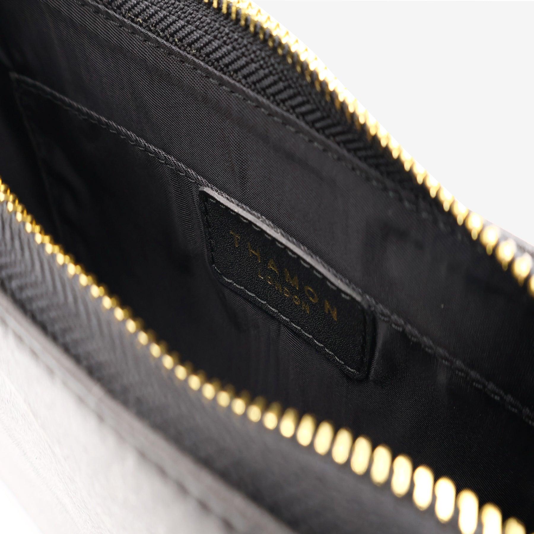 Inside view of the Mila Black Vegan Shoulder Bag showing the internal pocket with Thamon logo and zippered closure.