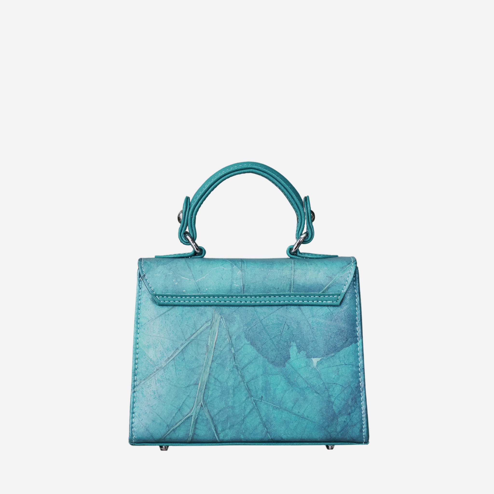 Back view of a teal-colored women's handbag with a subtle leaf-like texture. The bag features a single top handle connected by silver-tone hardware. The back of the bag has a smooth flap closure with stitched detailing and the same textured material on the main body. The base is equipped with four silver-tone metal feet.
