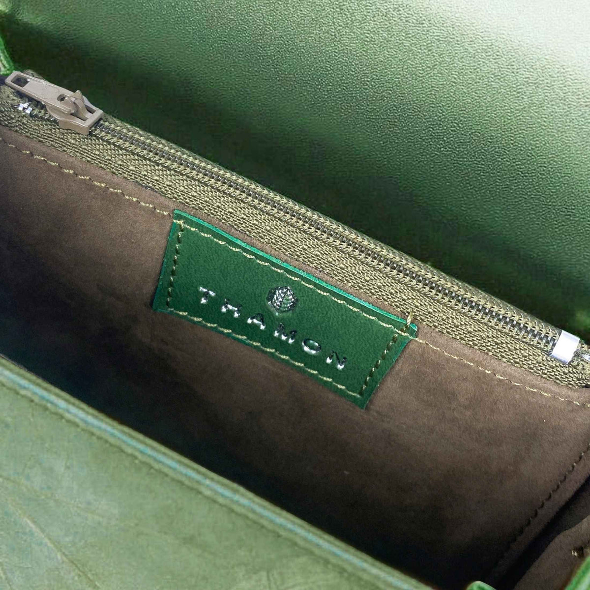 Inside view of the BOX crossbody bag in Olive Green, showing the interior compartment, zip pocket and THAMON label.