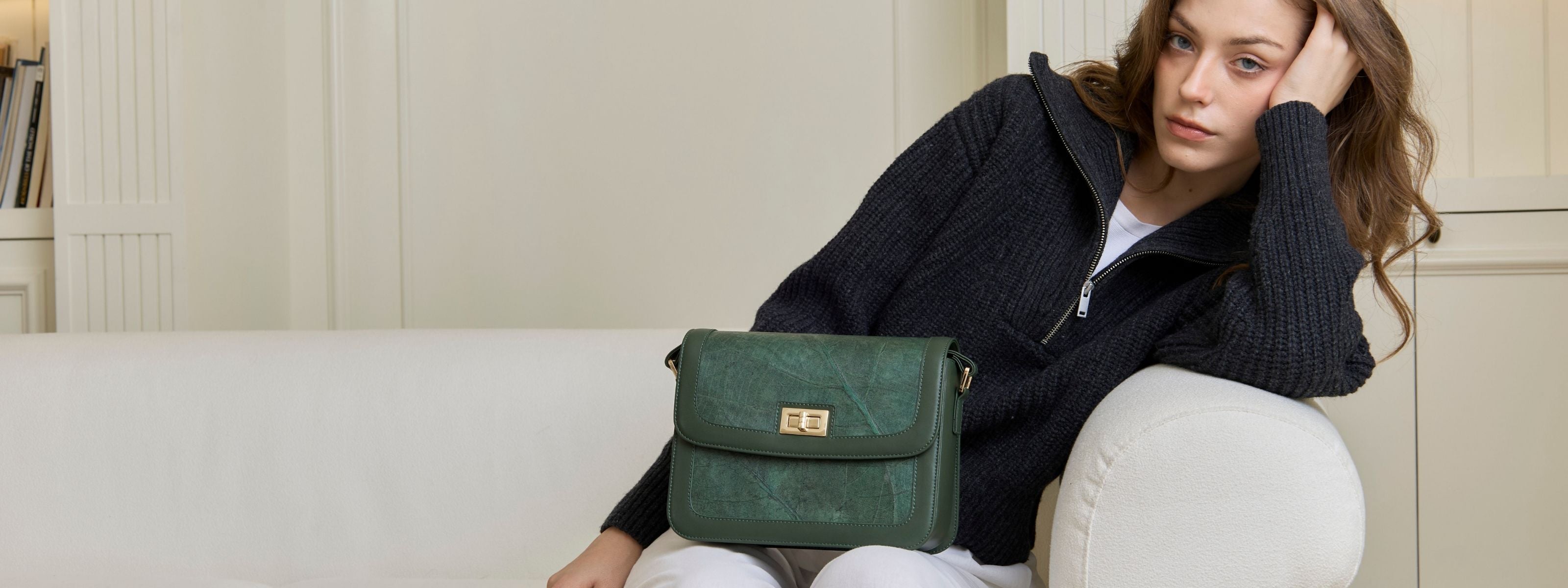 Woman sitting on sofa with forest green Copenhagen vegan crossbody bag by Thamon