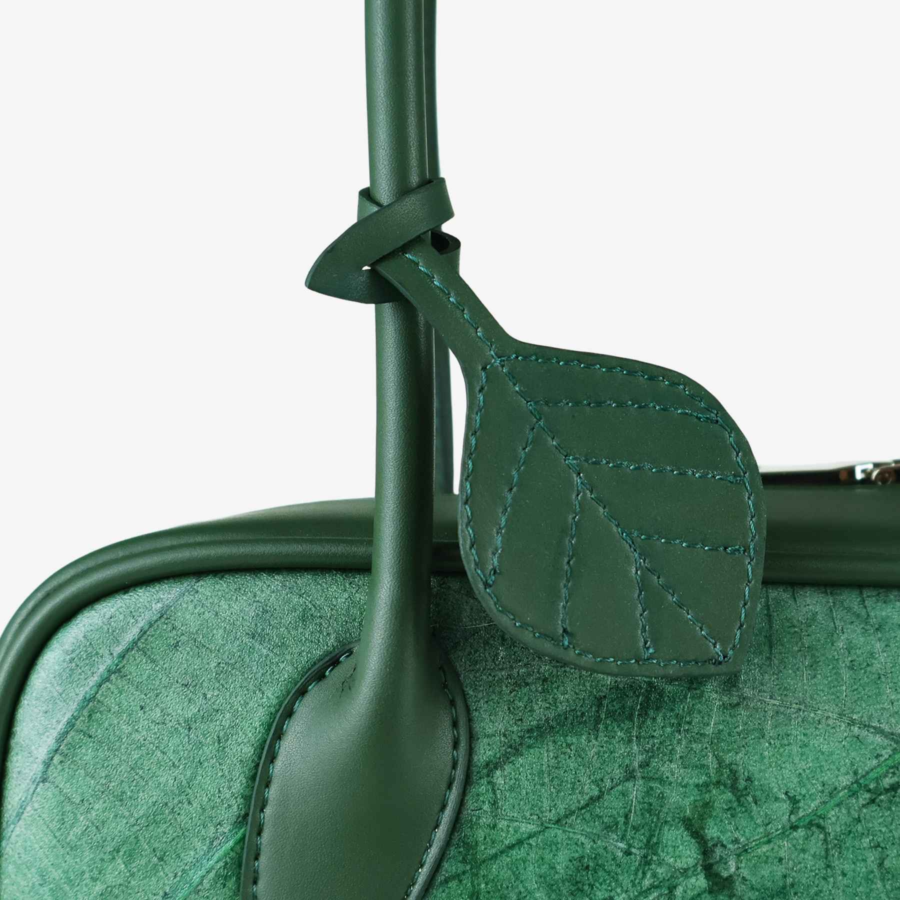 Close-up of leaf-shaped charm on Craugette bag in forest green leaf leather