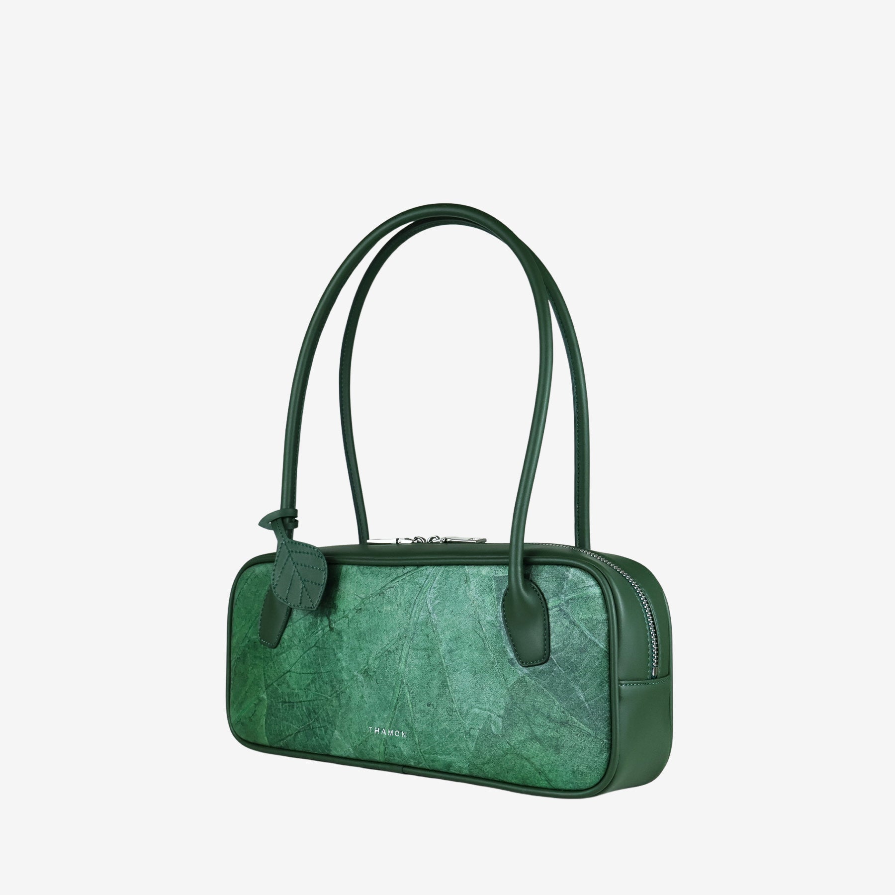 Green leaf-patterned vegan leather shoulder bag with a leaf charm. Sustainable fashion accessory.