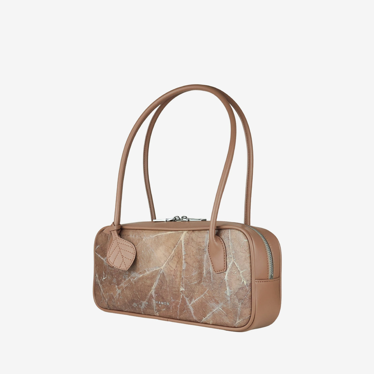 Angled view of the THAMON CRAUGETTE shoulder bag in Taupe, showing the leaf-textured front, smooth side panel and leaf-shaped charm.