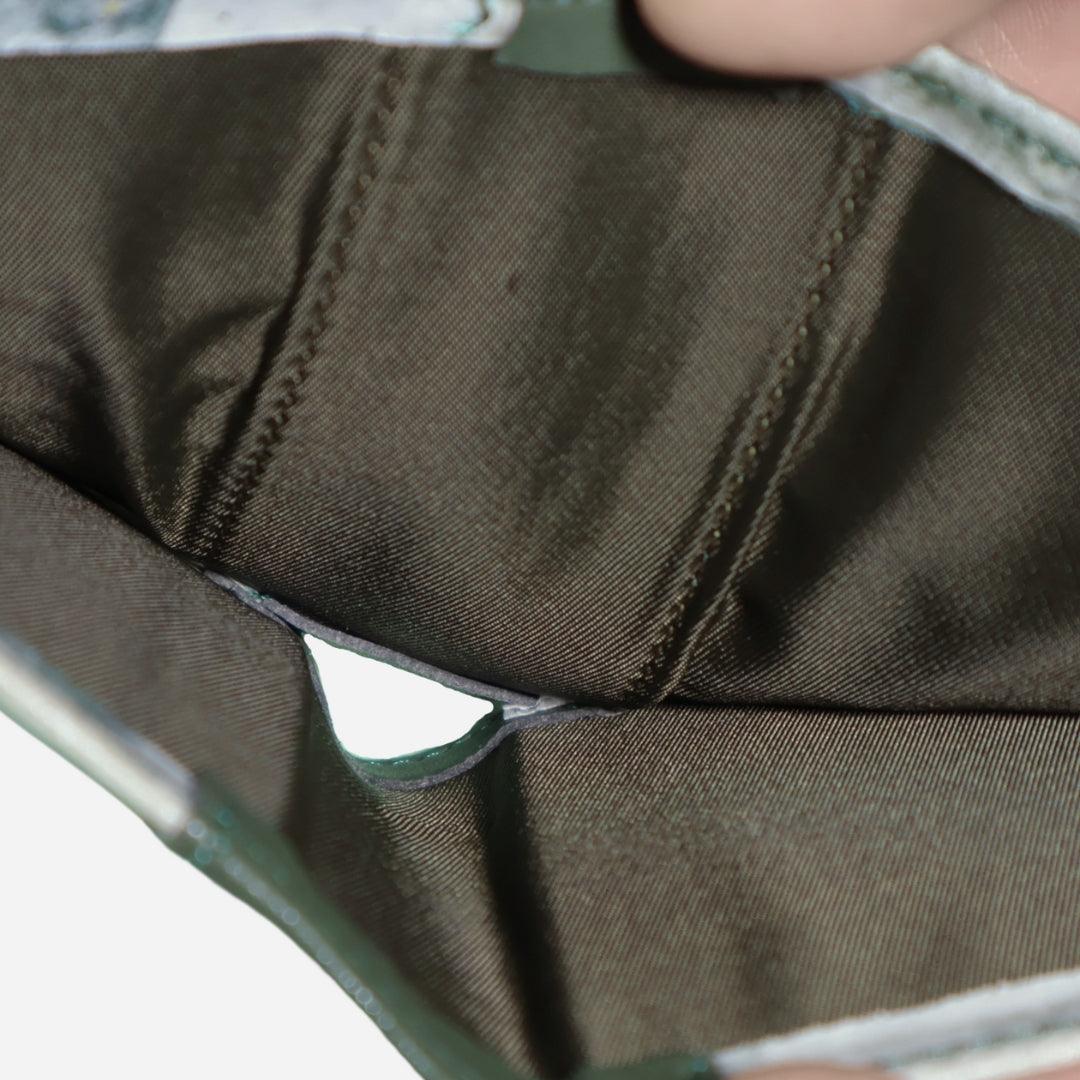 Close-up view of the interior of a wallet, showing a brown fabric lining with visible stitching. The image highlights the compartments and stitching details inside the wallet.