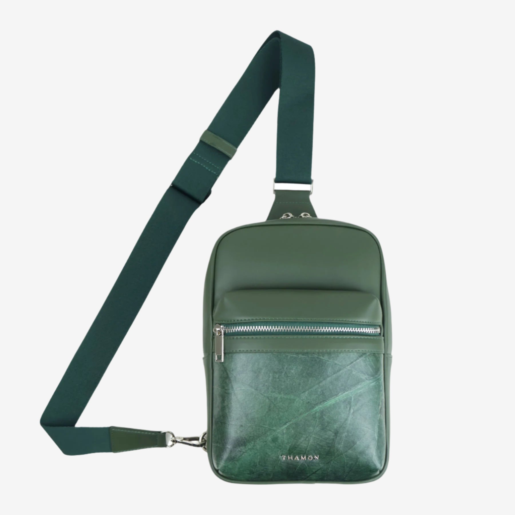 Full front view of Nomad sling bag in forest green with adjustable strap, front zip pocket, and natural leaf pattern panel