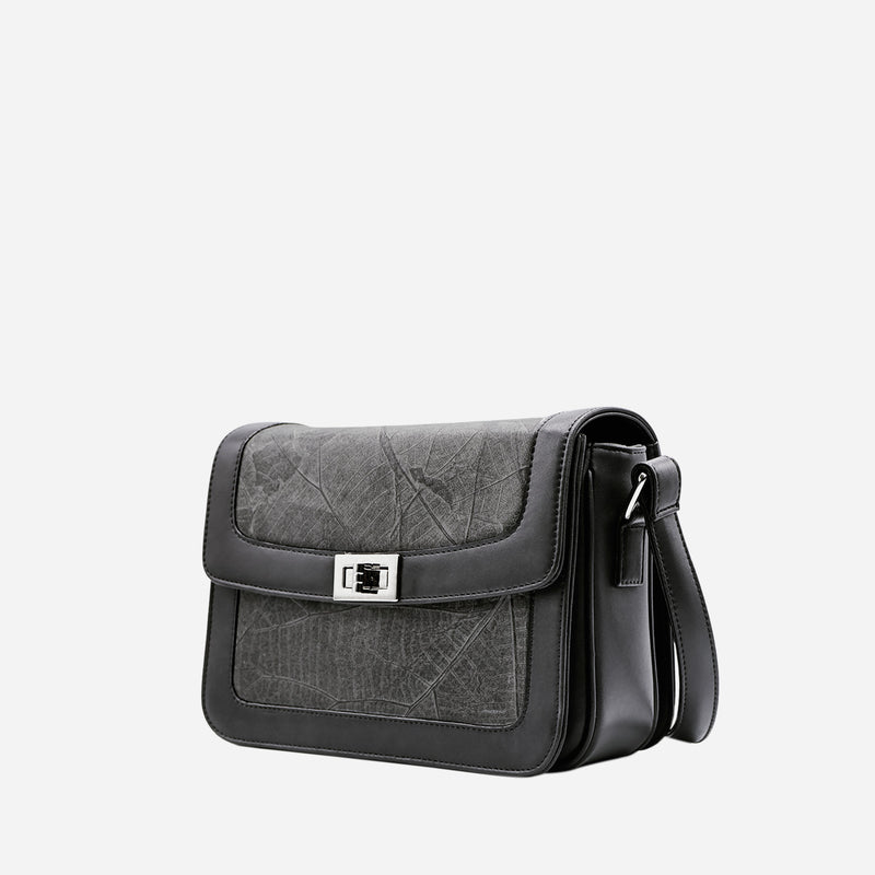 Side view of Molly Crossbody Bag in Black Vegan Leather by Thamon, featuring detailed leaf texture and secure twist-lock closure