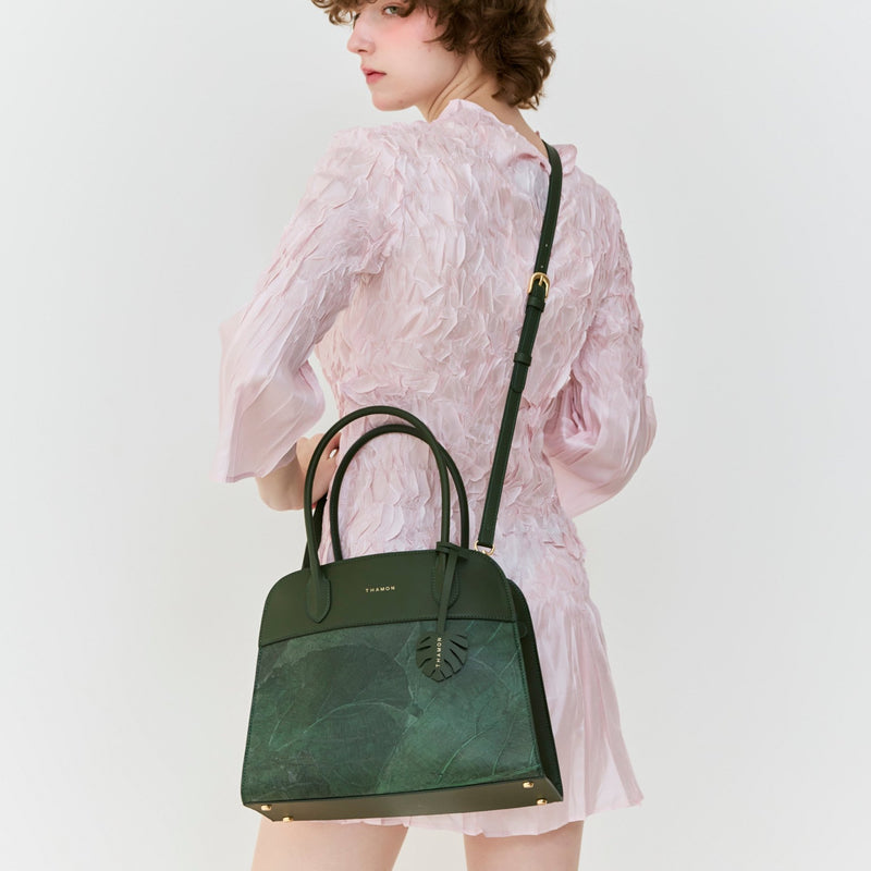 Front view of Thamon Sloane bag in forest green, worn on model's back, crafted from real leaf leather with dual handles and crossbody strap