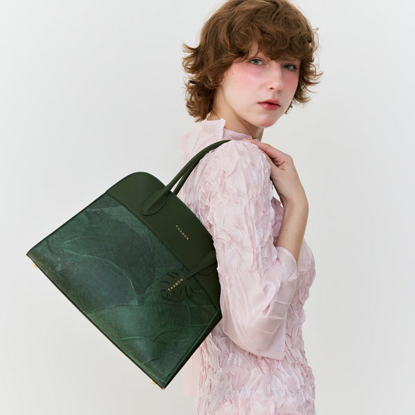 Model carrying the Thamon Sloane shoulder bag in forest green made from real leaf leather