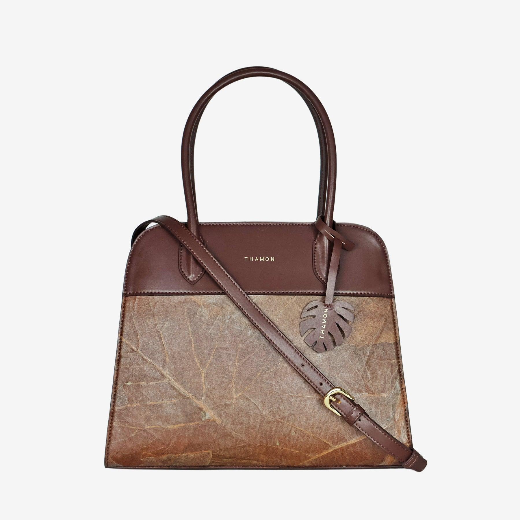 Sloane tote bag in spice brown vegan leather with a pressed leaf pattern, featuring an adjustable crossbody strap, sturdy top handles, and a decorative leaf-shaped tag on the front