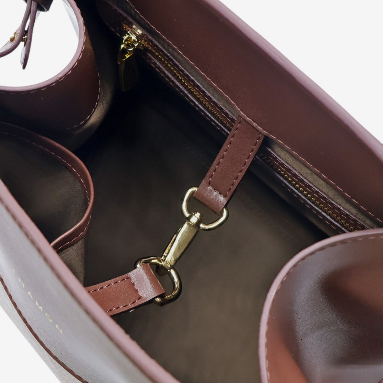 Interior view of the Sloane tote bag in spice brown vegan leather, featuring multiple compartments, a zippered pocket, and gold-tone hardware, including a clasp for added functionality