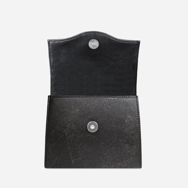 Open black leaf leather box bag from Thamon London, highlighting the contrasting textures between the smooth interior and the leaf-patterned exterior with a visible silver snap button for secure closure.