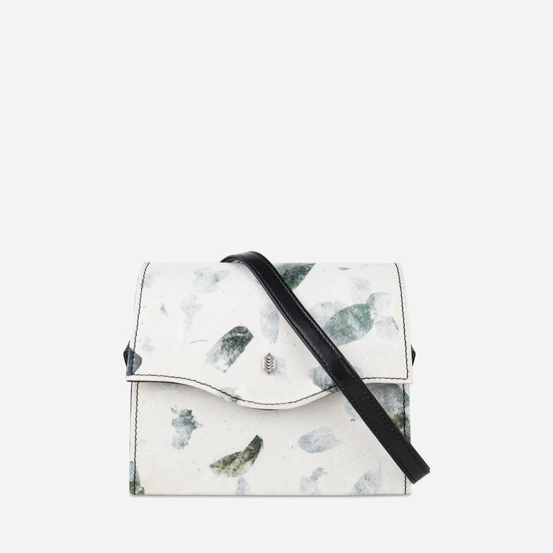 Front view of Thamon's camouflage leaf box bag, showcasing the unique white and green leaf pattern, a secure front flap with a magnetic closure, and a contrasting black vegan leather strap for a modern touch.