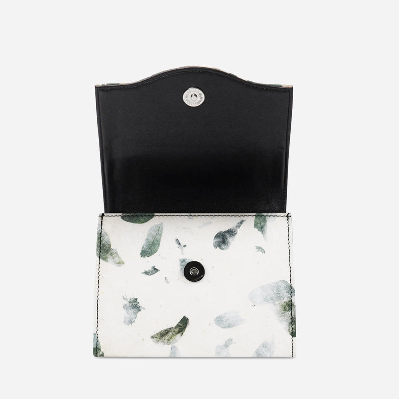 Open view of the Thamon camouflage leaf box bag revealing the black interior, a secure snap button closure, and the white exterior with a natural green leaf camouflage pattern.