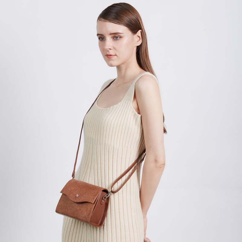 A woman in a cream ribbed dress models the Thamon Spice Brown Leaves Box Bag, a vegan crossbody with a leaf-textured surface and brown tan strap, against a light studio background.